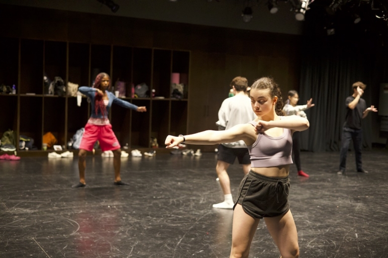 Tisch Summer High School Drama students stand with both arms horizontally held out to the side in a drama studio.